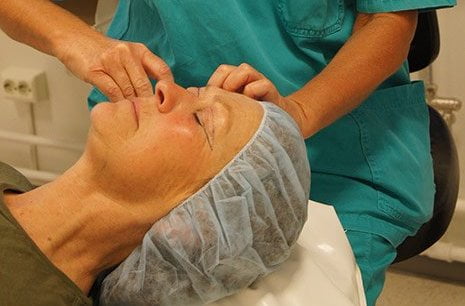 Kirurg som utfører øyelokkskirurgi på pasient.