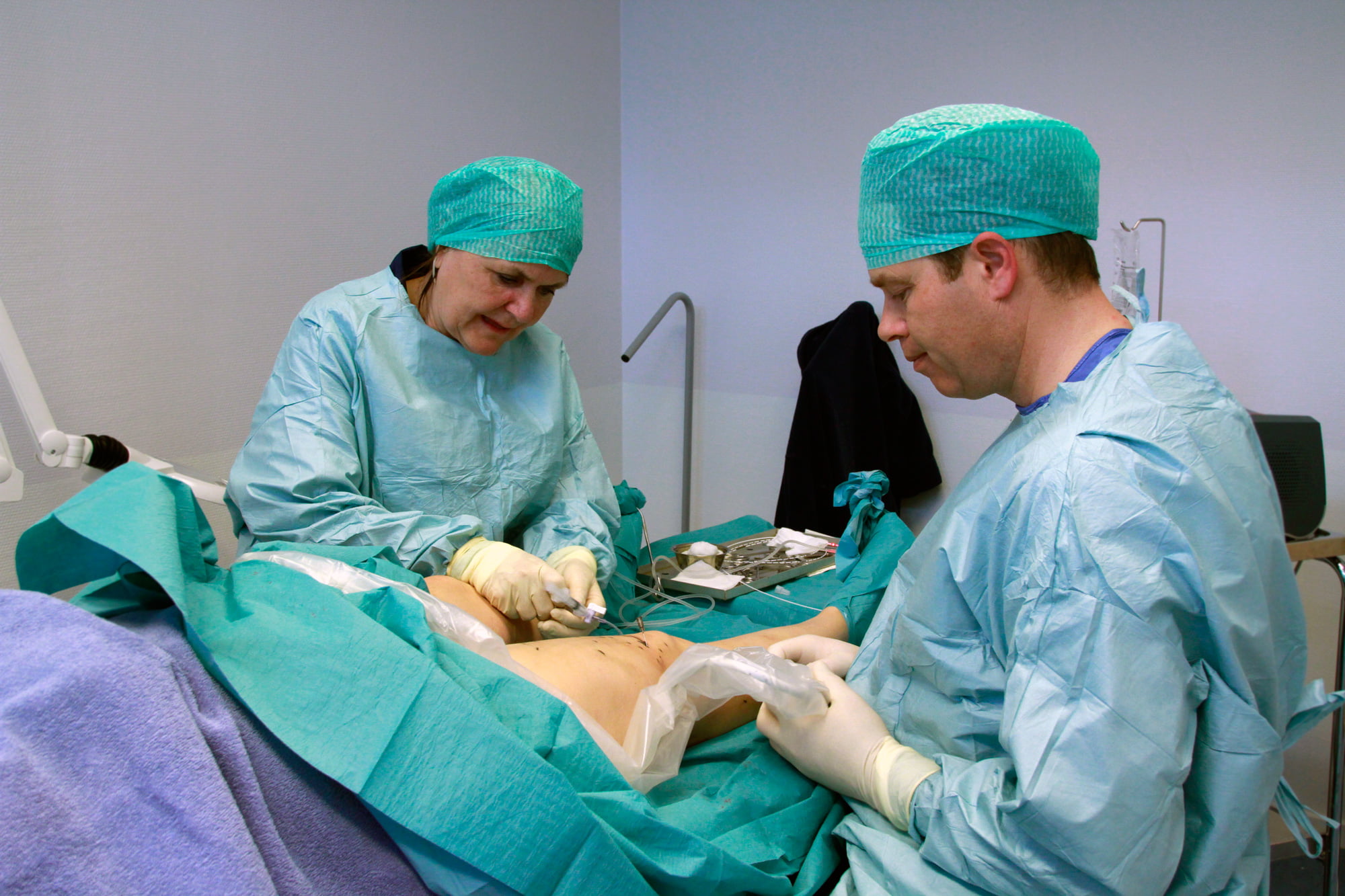 To personer som utfører en operasjon av åreknuter i beina.